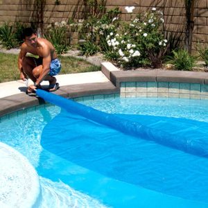 A solar cover being laid out on a pool